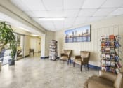 Thumbnail 12 of 30 - Sitting area with large windows and towers of paperback books for residents to enjoy