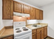 Thumbnail 13 of 30 - residential kitchen at Sundale Manor Apartments with white appliances and wood cabinetry
