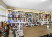 Thumbnail 8 of 30 - entire wall full of book shelves with books and reading table in library