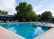 Thumbnail 6 of 26 - a swimming pool with chaise lounge chairs and trees in the background