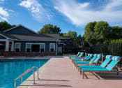 Thumbnail 7 of 26 - a swimming pool with chaise lounge chairs and clubhouse in the background