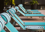 Thumbnail 3 of 26 - a row of blue chaise lounges with a table