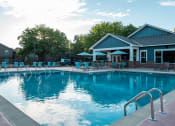 Thumbnail 2 of 26 - a swimming pool with lounge chairs and umbrellas in front of the clubhouse