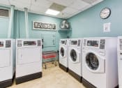 Thumbnail 13 of 17 - laundry room with washers and dryers, rolling cart, fan, and coin machine