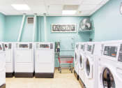 Thumbnail 12 of 17 - laundry room with washers and dryers, rolling cart, fan, and coin machine