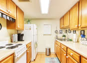 Thumbnail 7 of 17 - galley kitchen with ample cabinetry, white appliances, and wood-style floors