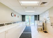 Thumbnail 21 of 24 - large laundry center with washers, dryers, and carts