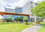 Thumbnail 3 of 24 - lush landscaping and outdoor seating in front of large lobby windows