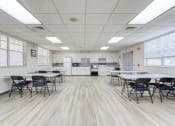 Thumbnail 11 of 23 - community room with kitchen and tables and chairs for residents