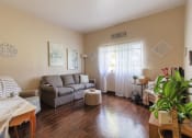 Thumbnail 12 of 16 - living room with hardwood-style flooring, large window, and model furnishings