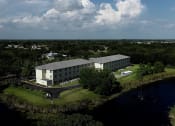 Thumbnail 12 of 12 - Villa Vincente Senior Apartments in For Myers, FL surrounded by trees beside water