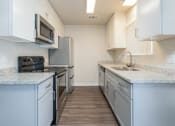 Thumbnail 6 of 17 - Alternate view of kitchen with stone counters, white cabinets, stainless appliances