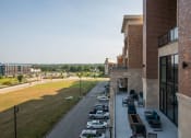 Thumbnail 62 of 75 - view of the outside of a brick building with cars parked out front and outdoor lounge seating at The Apex at CityPlace, Overland Park, Kansas
