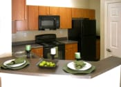 Thumbnail 7 of 13 - A kitchen and bar area with black appliances and wood cabinets