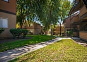 Thumbnail 6 of 18 - a sidewalk between two apartment buildings with grass and trees