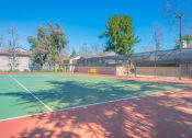 Thumbnail 4 of 22 - a tennis court with a fence and houses in the background