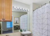 Thumbnail 6 of 22 - A bathroom with a white toilet, sink, and shower curtain.