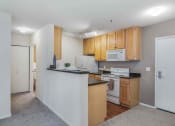 Thumbnail 5 of 22 - A kitchen with wooden cabinets and white appliances.