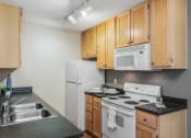 Thumbnail 7 of 22 - A kitchen with a white refrigerator, white microwave, and white stove.