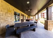 Thumbnail 25 of 39 - Outdoor Clubhouse Lounge Area with Large Bench at Legacy Creekside Apartments, San Antonio, Texas