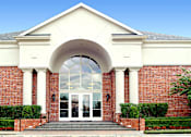Thumbnail 28 of 50 - img src="clubhouse.png" alt="red brick exterior of building with glass door and arch"
