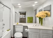 Thumbnail 37 of 50 - Spacious bathroom with oval soaking tub with glass enclosure, cultured marble vanity, glass shower, and built-in vanity at The Lanesborough Apartments in Houston.