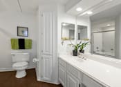 Thumbnail 8 of 50 - Spacious bathroom with oval soaking tub with glass enclosure, cultured marble vanity, glass shower, and built-in vanity at The Lanesborough Apartments in Houston.