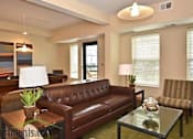 Thumbnail 2 of 26 - A brown leather couch sits in a living room with a glass table in front of it.