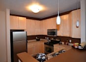 Thumbnail 8 of 26 - A kitchen with wooden cabinets and a refrigerator.