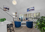 Thumbnail 22 of 32 - A living room with a staircase and a blue sofa.
