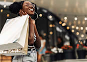 Thumbnail 4 of 7 - Woman with shopping bags walking, seen from the side.
