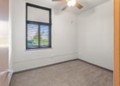 Thumbnail 15 of 31 - a bedroom with plush carpeting, a window, and an illuminated ceiling fan