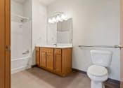 Thumbnail 16 of 31 - a bathroom with a sink vanity with mirror and lights, a toilet, and a shower/tub