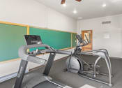 Thumbnail 21 of 31 - a fitness center with cardio machines, wall chalkboards and a mirror
