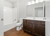 Thumbnail 11 of 31 - a bathroom with a large sink vanity and mirror, toilet, and shower/tub 