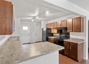 Thumbnail 4 of 31 - A kitchen with track lighting, wood cabinets, and black appliances at Muskego School Apartments