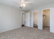 Thumbnail 10 of 11 - A room with a ceiling fan and carpeted floor.