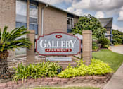 Thumbnail 5 of 11 - A sign for Gallery Apartments is in front of a building.