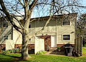 Thumbnail 8 of 27 - A house with a white door and a tree in front.