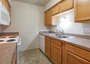 Thumbnail 27 of 27 - A kitchen with a white stove top oven, a white dishwasher, and wooden cabinets.