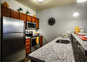Thumbnail 3 of 22 - Liberty Gateway Apartments, Salt Lake City, Utah, kitchen with a granite countertop and a clock on the wall.