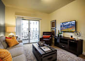 Thumbnail 4 of 22 - Liberty Gateway Apartments, Salt Lake City, Utah, living room with a grey couch, a red chair, a black coffee table, and a painting on the wall.