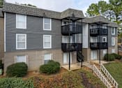 Thumbnail 6 of 13 - A grey apartment building with black railings and white windows.