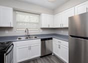 Thumbnail 11 of 13 - A kitchen with white cabinets and stainless steel appliances.