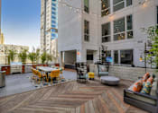 Thumbnail 4 of 73 - A wooden deck with a table and chairs is surrounded by buildings.