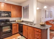 Thumbnail 27 of 49 - a kitchen with wooden cabinets and black appliances