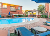 Thumbnail 6 of 49 - a swimming pool with lounge chairs and umbrellas in front of a building