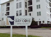 Thumbnail 1 of 25 - A white building with a sign that says Bay Cove in front of it.
