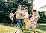 Thumbnail 3 of 12 - Family having fun playing soccer outside