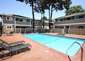 Thumbnail 3 of 22 - A swimming pool surrounded by lounge chairs and trees.